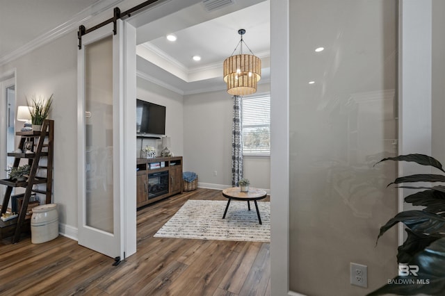 living room featuring ornamental molding, a barn door, dark hardwood / wood-style flooring, and a raised ceiling