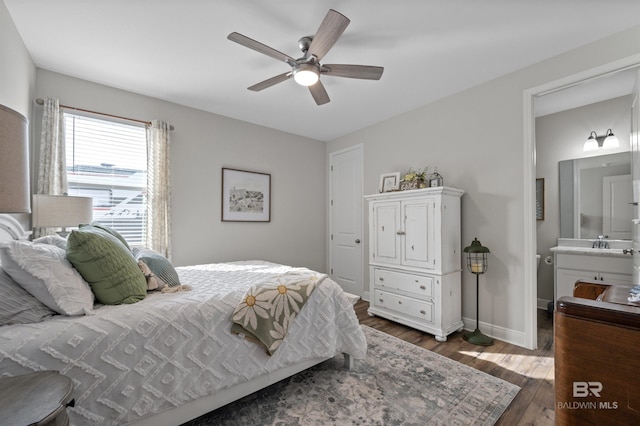 bedroom featuring dark hardwood / wood-style flooring, sink, ensuite bath, and ceiling fan