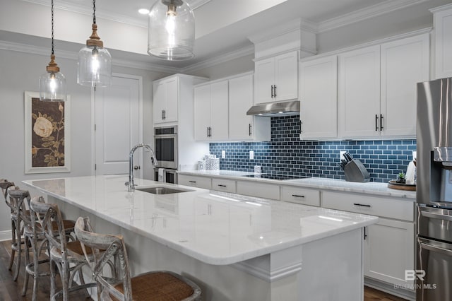 kitchen with pendant lighting, light stone countertops, stainless steel appliances, and a center island with sink