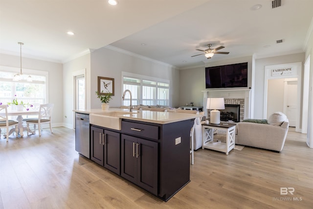 kitchen featuring stainless steel dishwasher, a fireplace, ceiling fan, light countertops, and a sink