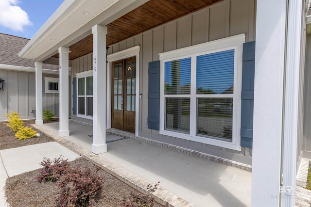 property entrance featuring roof with shingles, covered porch, board and batten siding, and french doors