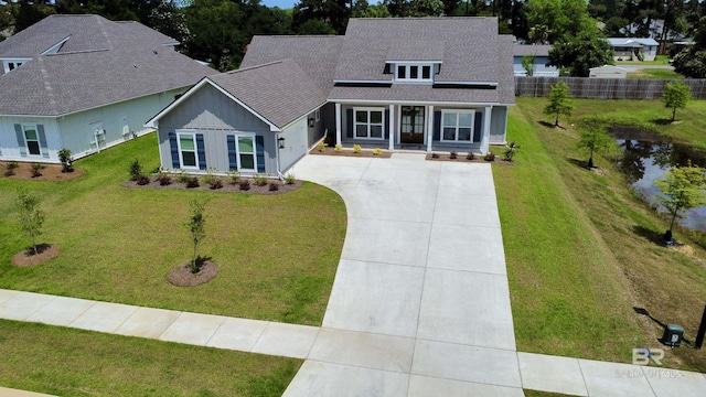 view of front of home with a shingled roof, a front lawn, fence, and driveway