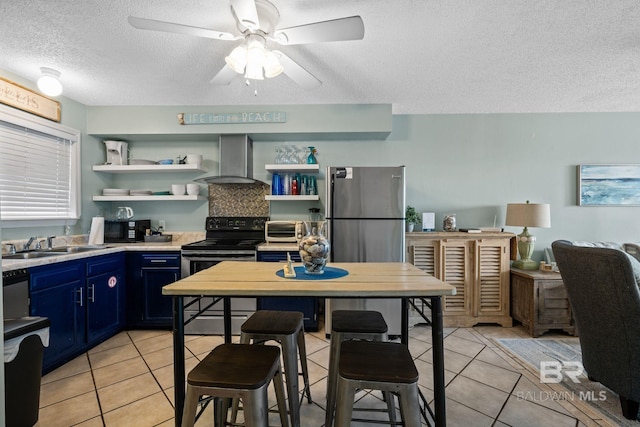 kitchen with wall chimney range hood, sink, light tile patterned flooring, black / electric stove, and blue cabinets