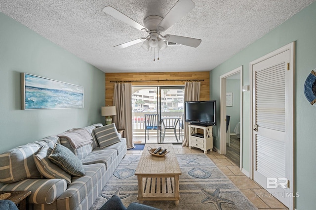 tiled living room with ceiling fan, wooden walls, and a textured ceiling