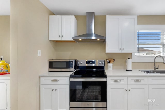 kitchen with wall chimney exhaust hood, sink, white cabinetry, and stainless steel appliances