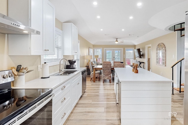 kitchen featuring stainless steel appliances, sink, light wood-type flooring, white cabinets, and a center island