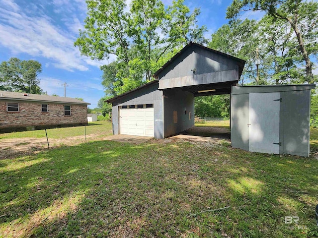 view of shed / structure with a garage and a lawn