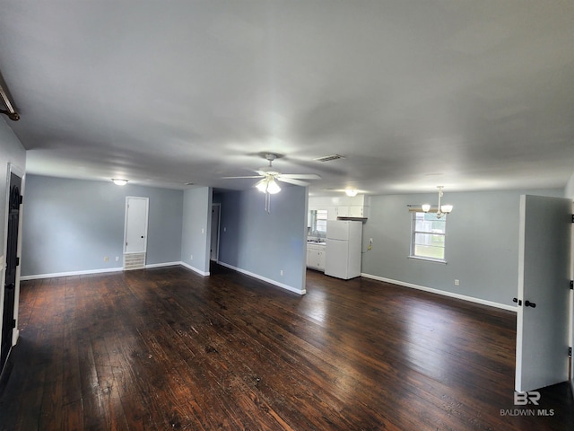 empty room featuring ceiling fan with notable chandelier and dark hardwood / wood-style flooring