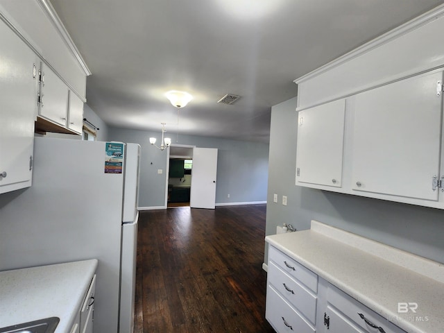 kitchen featuring white cabinetry, white fridge, wood-type flooring, and an inviting chandelier