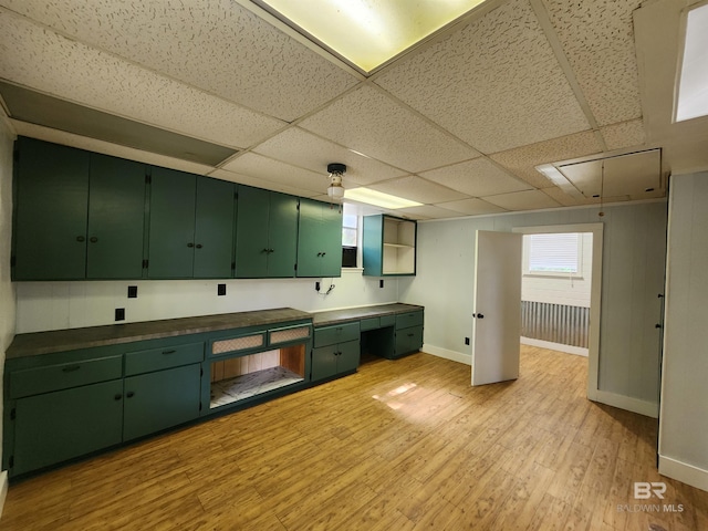 kitchen featuring light hardwood / wood-style flooring, green cabinetry, and a drop ceiling