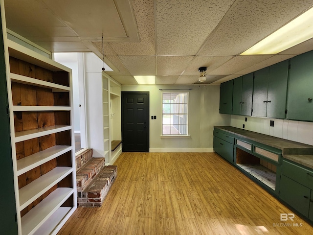 kitchen with light hardwood / wood-style floors, built in shelves, green cabinetry, and a drop ceiling