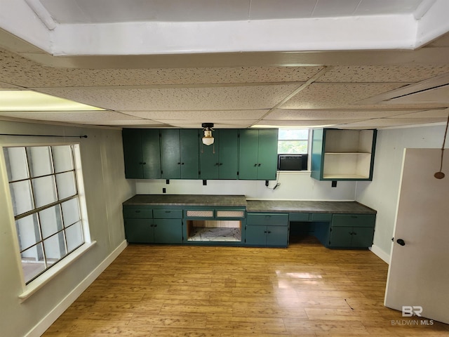 kitchen with a paneled ceiling, green cabinets, and light hardwood / wood-style flooring