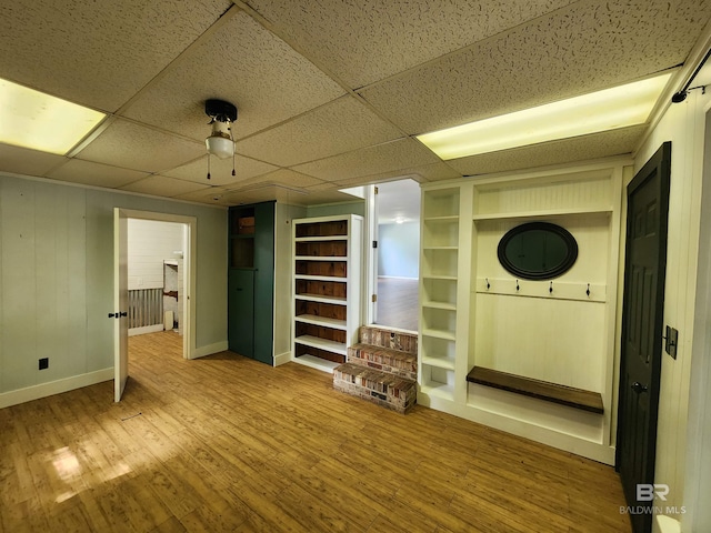 basement featuring built in shelves, a paneled ceiling, and hardwood / wood-style floors