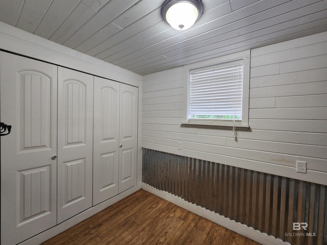 unfurnished bedroom with wood walls, dark hardwood / wood-style flooring, and a closet