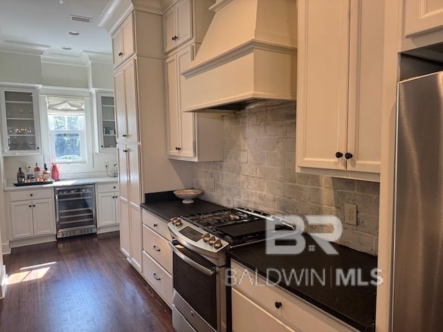 kitchen featuring premium range hood, stainless steel range with gas cooktop, beverage cooler, and white cabinets