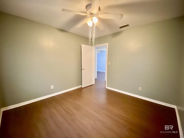 unfurnished room featuring baseboards, ceiling fan, visible vents, and dark wood-style floors