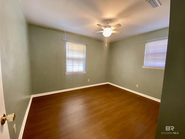 unfurnished room with baseboards, visible vents, a ceiling fan, and wood finished floors
