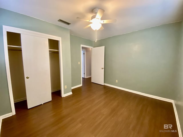 unfurnished bedroom featuring a closet, baseboards, ceiling fan, visible vents, and wood finished floors