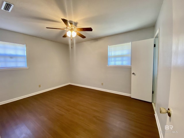 empty room featuring ceiling fan, baseboards, visible vents, and wood finished floors