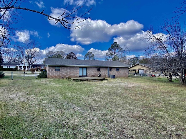 rear view of house featuring a yard, a deck, a fenced backyard, and brick siding