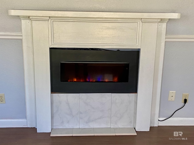 interior details featuring a warm lit fireplace and wood finished floors