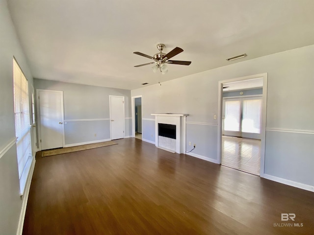 unfurnished living room with a ceiling fan, a fireplace, dark wood finished floors, visible vents, and baseboards