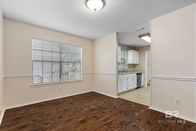 5645 Green Tree Rd, Mobile, AL 36609 - unfurnished dining area featuring a sink, light wood-type flooring, baseboards, and a textured ceiling