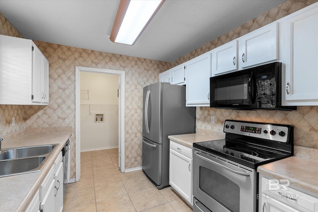 5645 Green Tree Rd, Mobile, AL 36609 - kitchen with stainless steel appliances, a sink, white cabinetry, light countertops, and wallpapered walls
