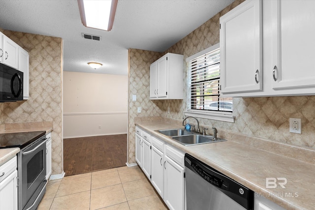 5645 Green Tree Rd, Mobile, AL 36609 - kitchen featuring stainless steel appliances, a sink, white cabinetry, baseboards, and a textured ceiling