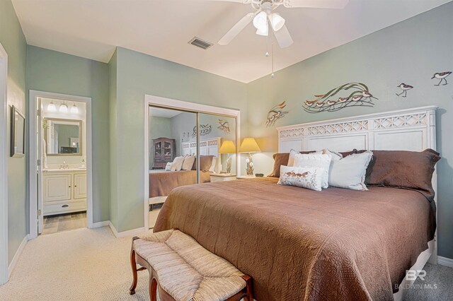 carpeted bedroom featuring a closet, ceiling fan, and ensuite bathroom