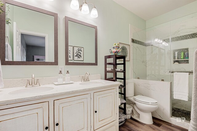 bathroom with toilet, a tile shower, wood-type flooring, and vanity