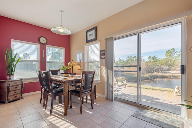 dining space featuring light tile patterned floors and a water view