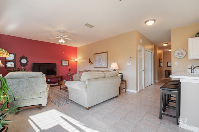 tiled living room featuring ceiling fan and sink