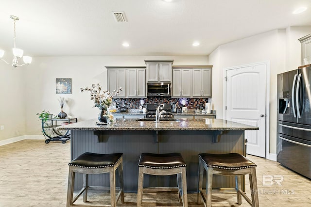 kitchen featuring a center island with sink, gray cabinets, sink, and stainless steel appliances