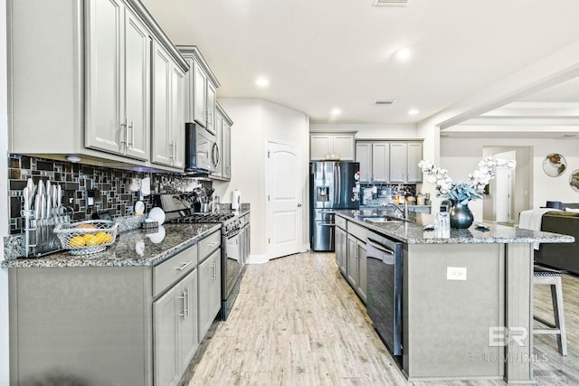 kitchen featuring gray cabinetry, sink, light wood-type flooring, appliances with stainless steel finishes, and tasteful backsplash