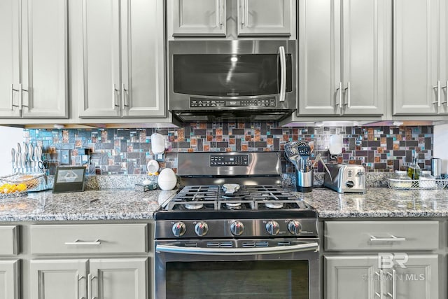 kitchen with decorative backsplash, appliances with stainless steel finishes, and light stone countertops