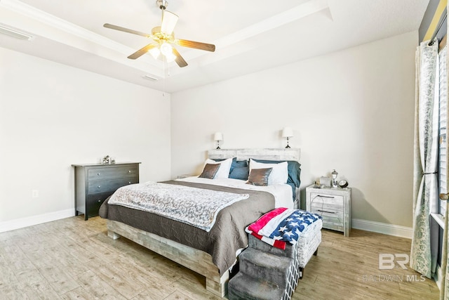 bedroom with a raised ceiling, light hardwood / wood-style flooring, and ceiling fan