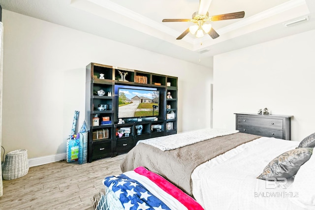 bedroom featuring a tray ceiling, ceiling fan, and light hardwood / wood-style flooring