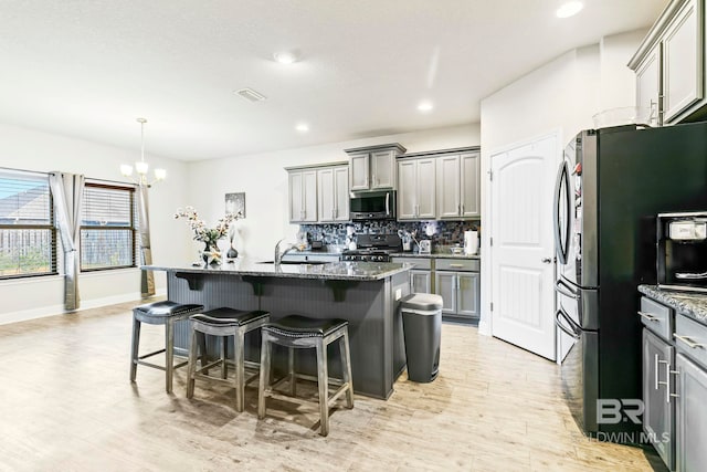 kitchen featuring a chandelier, stainless steel appliances, gray cabinets, and an island with sink