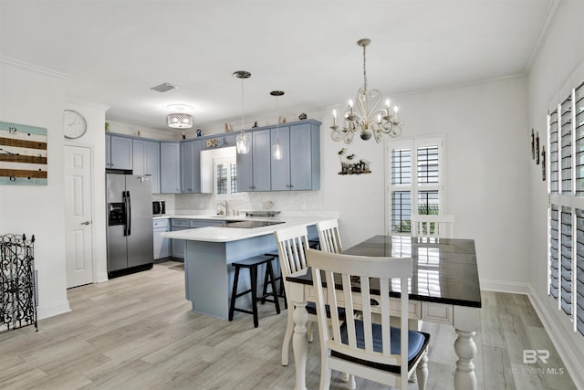 kitchen with kitchen peninsula, stainless steel refrigerator with ice dispenser, a kitchen bar, tasteful backsplash, and hanging light fixtures