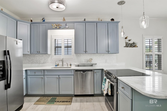 kitchen featuring kitchen peninsula, ornamental molding, stainless steel appliances, sink, and hanging light fixtures