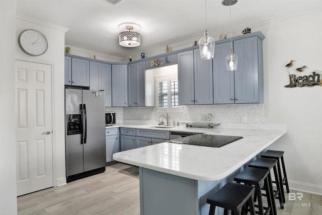 kitchen featuring stainless steel fridge, sink, kitchen peninsula, and hanging light fixtures