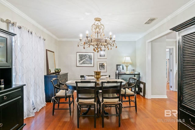 dining space featuring crown molding, wood-type flooring, and an inviting chandelier