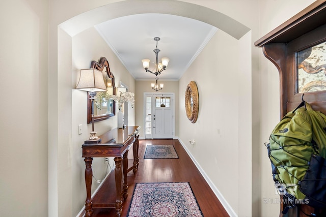 entryway featuring an inviting chandelier, ornamental molding, and dark wood-type flooring