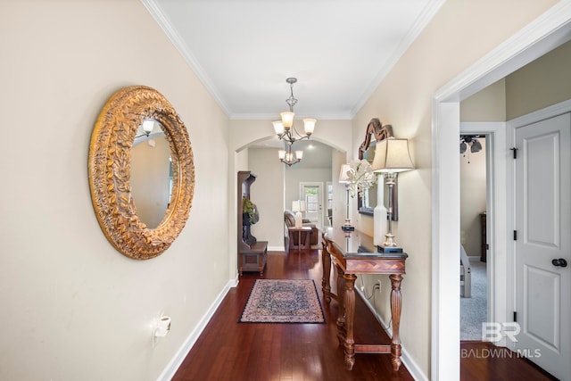 hall featuring crown molding, a chandelier, and dark wood-type flooring