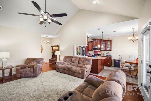 living room featuring light hardwood / wood-style flooring, high vaulted ceiling, and ceiling fan with notable chandelier