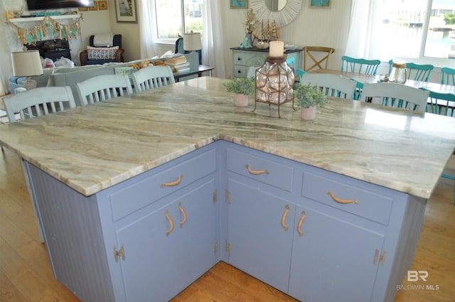 220 Shoreland Cir, Gulf Shores, AL 36542 - kitchen with light stone countertops, a kitchen breakfast bar, blue cabinetry, light hardwood / wood-style flooring, and a kitchen island