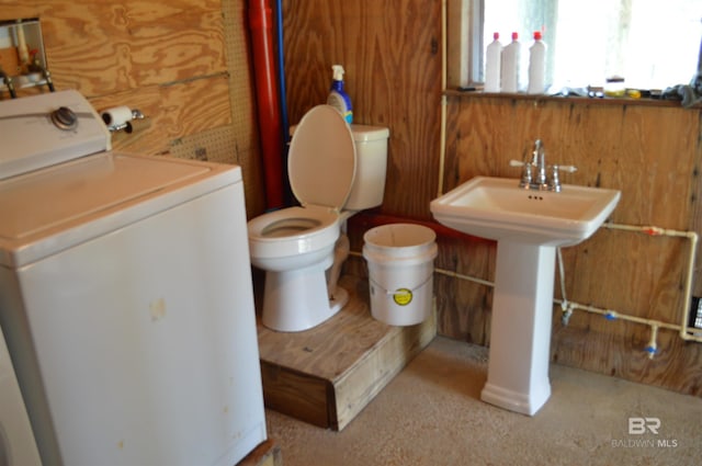 220 Shoreland Cir, Gulf Shores, AL 36542 - bathroom with toilet, washer / dryer, sink, and wooden walls