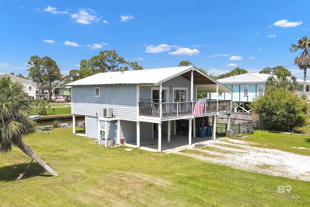 310 W 3rd Ave, Gulf Shores, AL 36542 - back of property with dirt driveway, a wooden deck, central AC unit, and a lawn