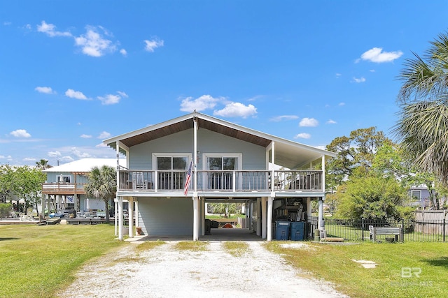 310 W 3rd Ave, Gulf Shores, AL 36542 - view of front of home featuring fence, a carport, driveway, and a front yard